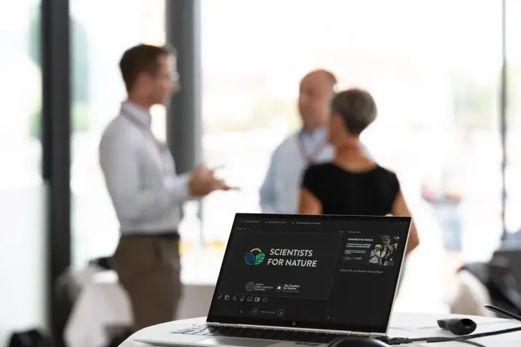Laptop displays "Scientists for Nature" logo and presentation slide.